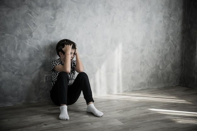 Premium Photo _ Sad boy sitting thinking sitting on the floor of the room against the house wall_